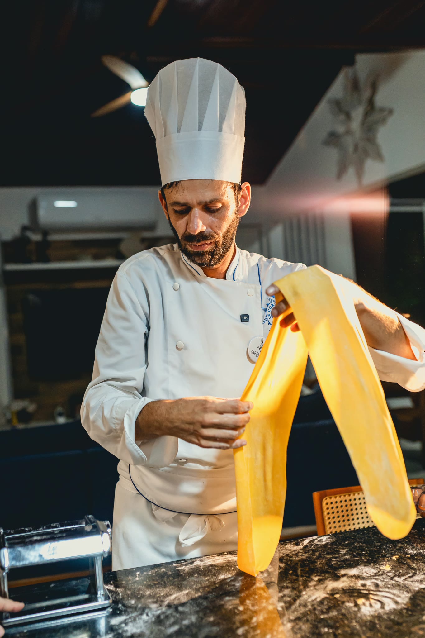 Chef Vitor Jover lifting a sheet of fresh pasta rolled out by hand