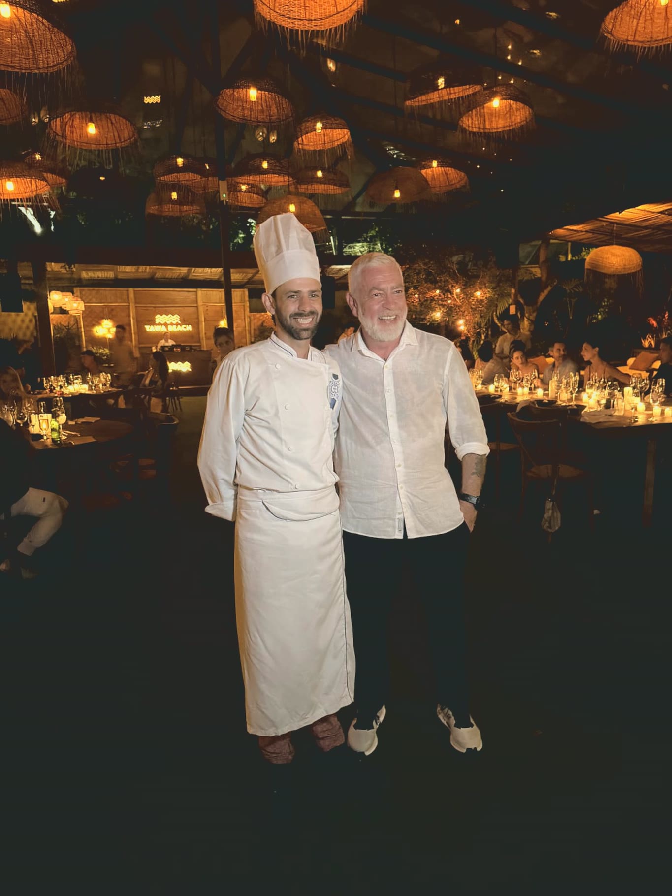 Chef Vitor Jover e Alex Atala lado a lado, sob as luminárias de palha do salão