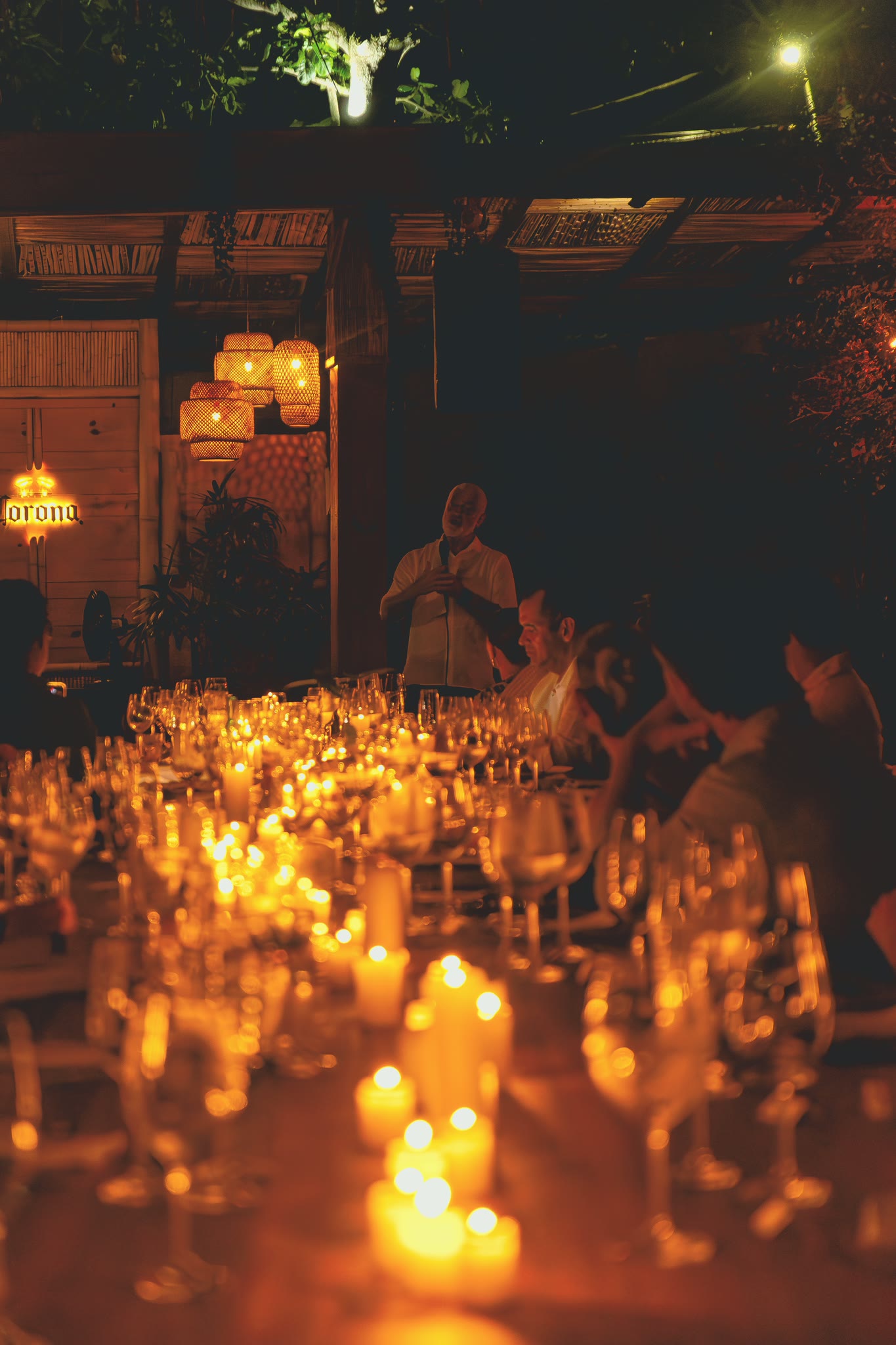 Mesa comprida posta com taças e velas, à noite, durante o jantar em Búzios