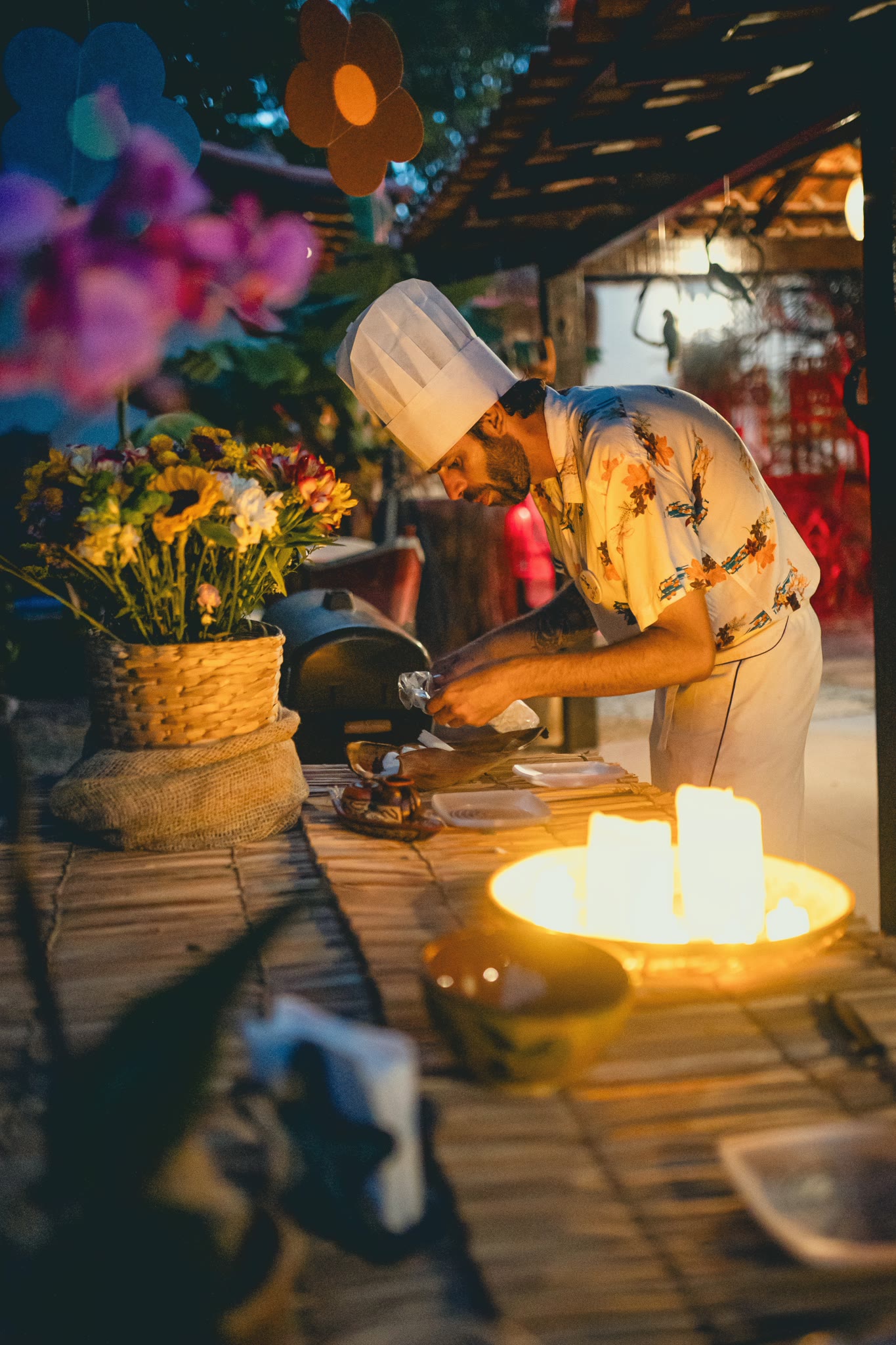Chef Vitor Jover at the embers, at night, among candles and flowers