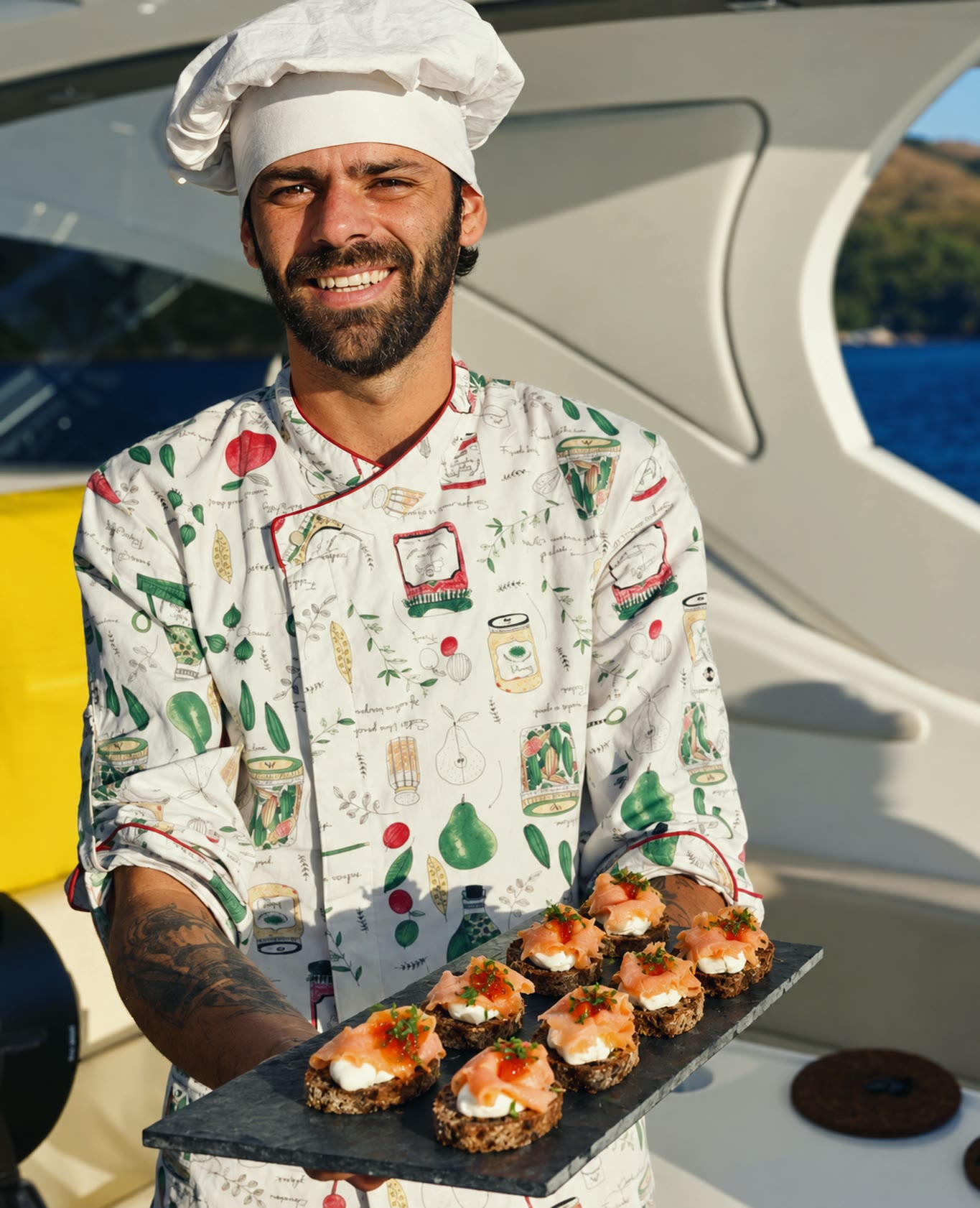 Chef Vitor Jover, sorrindo, segura uma bandeja de canapés a bordo de uma lancha